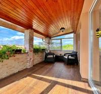 A glazed terrace with a wooden ceiling and flowers in a family house.