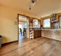 A kitchen in a family house with wooden furniture and ceramic tiles.