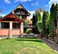 A family house in Levice with a landscaped garden, a gazebo, and trees.