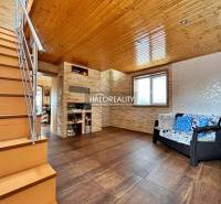 The interior of a family house with a wooden ceiling, staircase, and sofa set.