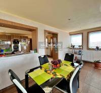 Dining room in a family house with a black table, chairs, and a view of the kitchen.