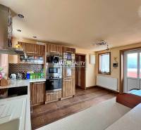 A kitchen in a family house with wooden furniture, built-in appliances, and a large window.