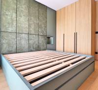 Bedroom with a bed with a slatted frame, wooden floor, and built-in wardrobe in a 2-room apartment.