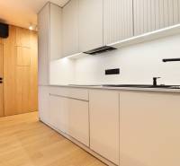 A kitchen in a 2-room apartment with wooden flooring and white cabinets.