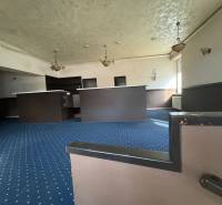 Interior of commercial spaces with carpets and a counter, illuminated by pendant lamps.