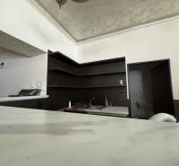 A kitchen unit with shelves and a sink in commercial premises, with doors leading to a room.