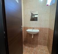 A toilet with a sink tiled in commercial premises.