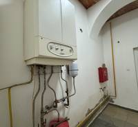 Kettle and piping in commercial premises, wall with slight signs of wear.