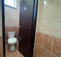 A restroom with closed doors in commercial premises, tiled with brown tiles.