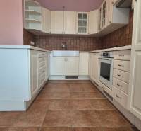 A kitchen in a 5 or more room apartment with white cabinets and brown tiles.