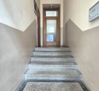 A hallway with a staircase leading to wooden doors in a 5 or more room apartment.