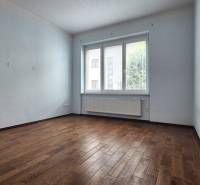 A spacious room with wooden flooring and a large window in a 5 or more room apartment.