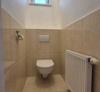 A toilet with tiles, a window, and a radiator in a 5 or more room apartment.