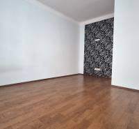 An empty room with a wooden floor and a decorative wall in a multi-room apartment.
