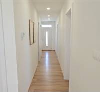 A bright hallway in a family house with wooden flooring and entrance doors.