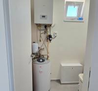 The interior of a family house with a boiler room containing a wall-mounted boiler and a water heater.