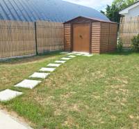 Garden of a family house in Nižná with a wooden cottage and a paved path.
