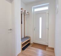 An entrance hall in a family house with white doors, a coat rack, and a bench for seating.