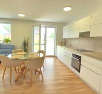 Open living room in a family house with a kitchen unit, table, and blue sofa.