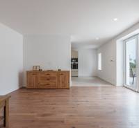 Interior of a family house with wooden flooring, a cabinet, and sliding doors to the terrace.