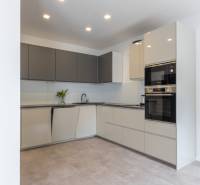 A kitchen in a family house with minimalist white-gray cabinets and built-in appliances.
