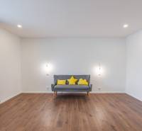 Gray sofa with yellow cushions in the living room of a family house, wooden floor.