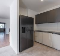 A modern kitchen in a family house with a black refrigerator and light cabinets.