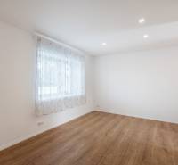 The interior of an empty room in a family house with wooden flooring and a curtain on the window.