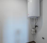 A boiler in the bathroom of a family house with white walls and tiles.