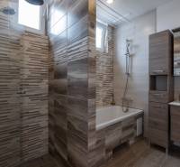 Bathroom with a bathtub, shower, and cabinets in a family house.