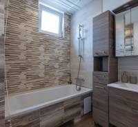 Bathroom with a bathtub, wooden furniture, and a sink in a family house.