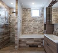 A bathroom in a family house with a bathtub, shower, and wooden cabinets.