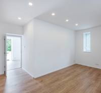 An empty room in a family house with wooden flooring and white walls.