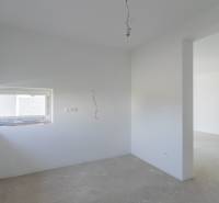 A bright room in a family house with a gray floor and a window.