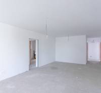 Spacious room in a family house with white walls and raw flooring.