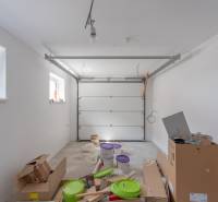 Unorganized garage in a family house, cardboard boxes, buckets, light walls.