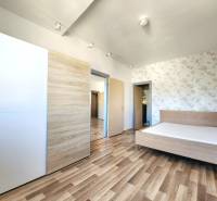 Bedroom with wooden flooring, a bed, and a built-in wardrobe in a two-room apartment.