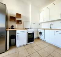 A kitchen in a 2-room apartment with appliances and minimalist wooden furniture.