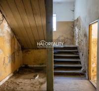 Abandoned commercial spaces with a staircase and damaged walls.