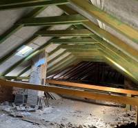 The ceiling of commercial premises with a wooden structure and building materials scattered on the floor.