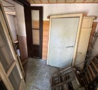 A narrow corridor in commercial premises with debris and old doors.