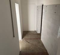A narrow interior with tiled flooring and a paneled wall in commercial premises.