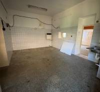 Interior of commercial premises with older tiles and flooring, empty room with a sink.