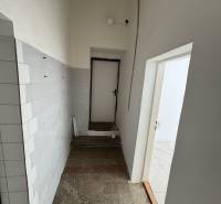 A narrow corridor with tiled walls and light in commercial premises.