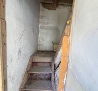 Narrow wooden staircase in commercial premises with white walls and beamed ceiling.