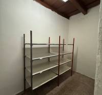 A storage room in commercial premises with a metal shelf and ceiling lighting.