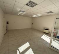 An empty commercial space with ceramic tiles and a plasterboard ceiling.