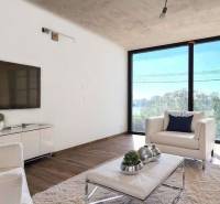 Living room in a cottage with large windows, white furniture, and a TV on the wall.