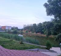Lake with a path in Senec, Vtáčia Street, between trees and residential buildings.