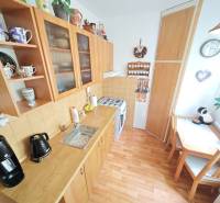 A kitchen in a 2-room apartment with wooden furniture, a dining corner, and decorations.